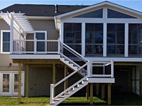 <b>Screened porch and deck with composite deck boards and white vinyl railing with black balusters. The screened porch has a gable style roof and is screened with Eze-Breeze sliding panel system that allows you to use your room all year round. The deck has a decorative trellis with lattice.</b>