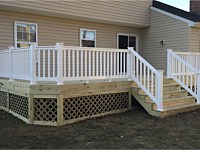 <b>Wood deck and stairs with white vinyl railing and lattice wrap underneath the deck.</b>