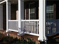 <b>White square columns with decorative accents with white vinyl railing attached to brick porch floor</b>