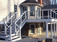 <b>Screened Porch and Deck project: Deck features composite deck boards with white composite railing and black aluminum balusters. Lighting has been integrated on the stairs with riser lights as well as the entire deck dressed with post cap lighting. The deck is wrapped in white fascia board, and the support beams and posts are also adorned with vinyl wrap. Deck drain system is used to create a usable space below the deck, complete with gutter system. The Screened Porch has a gable style roof and continues with the same deck boards.</b>