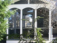 <b>Screened Porch with a gable style roof, complete with composite deck boards and white aluminum railing with black aluminum balusters. An arched finish was given to the vinyl wrap on the exterior perimeter of the room. The screening system includes Screeneze and Super Screen Mesh.</b>