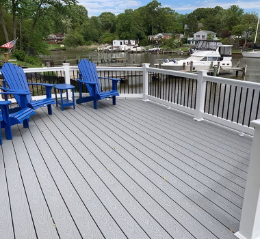 A riverfront deck with Trex Select Pebble Gray composite deck boards with white vinyl railing with black aluminum balusters