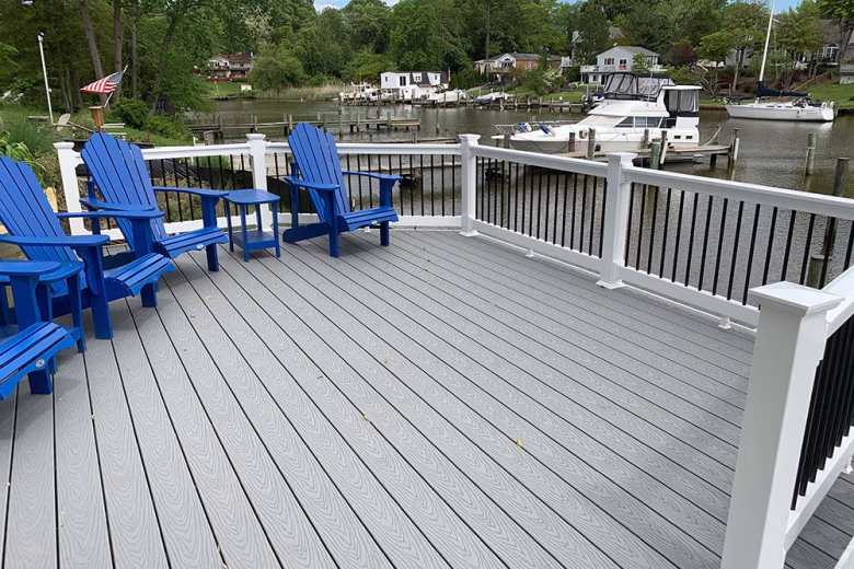 A riverfront deck with Trex Select Pebble Gray composite deck boards with white vinyl railing with black aluminum balusters