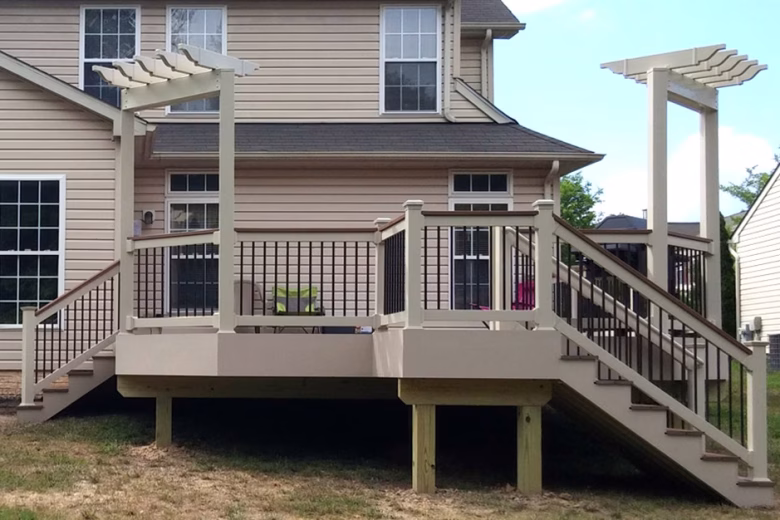 Composite deck with tan vinyl railing, matching cocktail rail, black balusters, and two tan trellis.