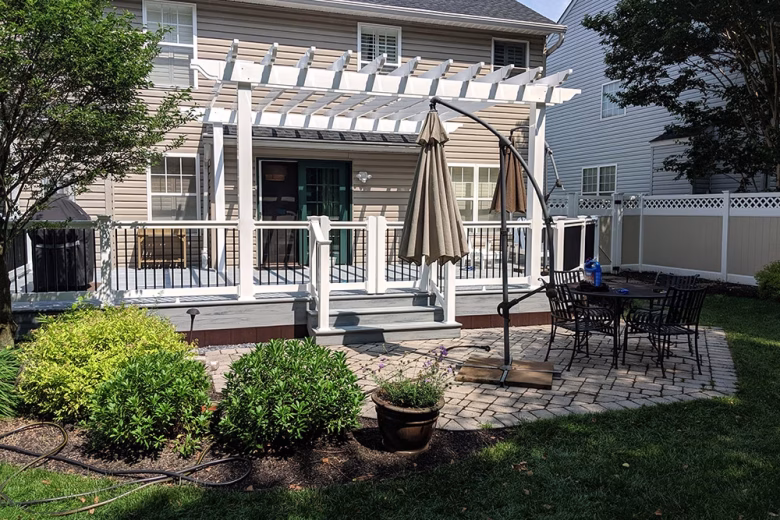 Trex Pebble Gray decking with white Washington vinyl railing, black round aluminum balusters, double gate, and white vinyl pergola.