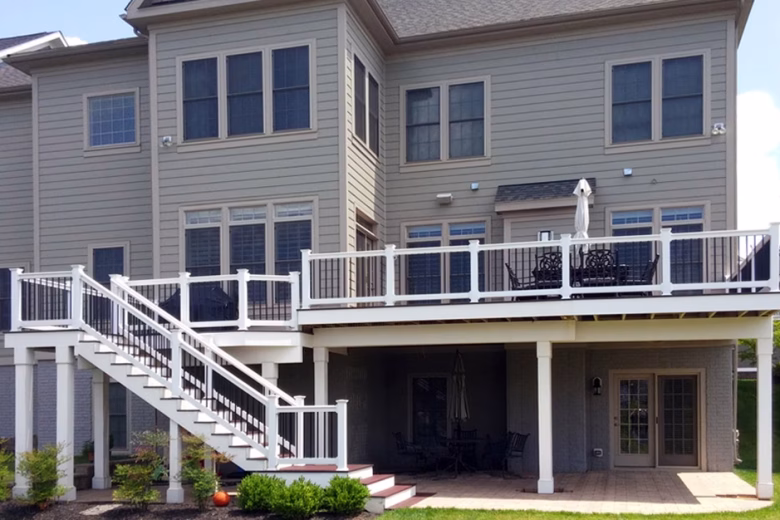 Trex composite deck boards with white Washington railing, black aluminum balusters, white vinyl wrap on support beams and posts, and fascia.