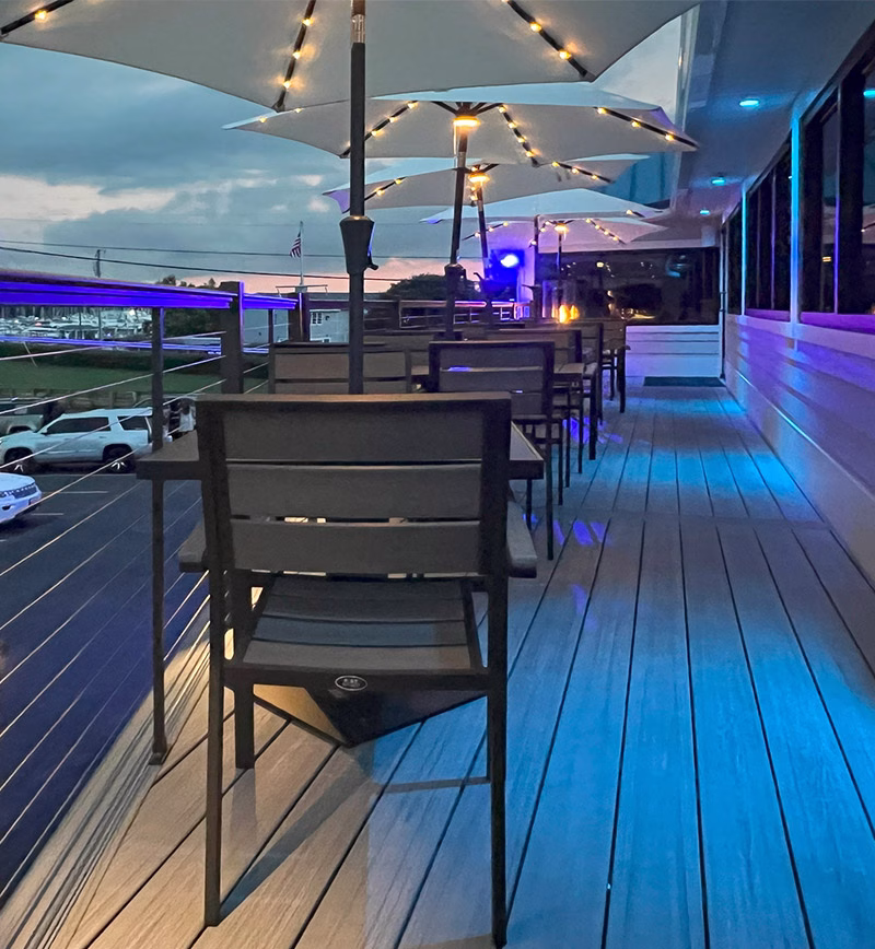 commercial restaurant deck with umbrellas and colored lights at dusk