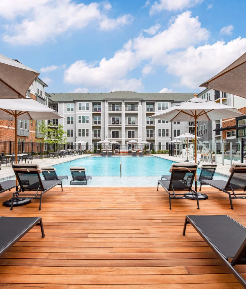 wood deck with chairs around a pool in an apartment complex