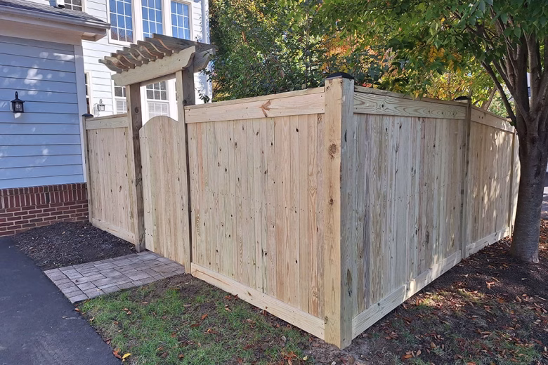 Pressure treated wood privacy fence with top and bottom fascia and arched gate with trellis
