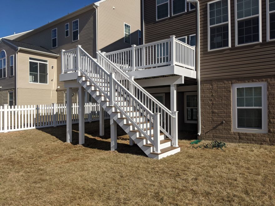 Nice deck with white vinyl railing and stairs to grade showing vinyl wrapped support beams + posts + fascia in Clarksville MD
